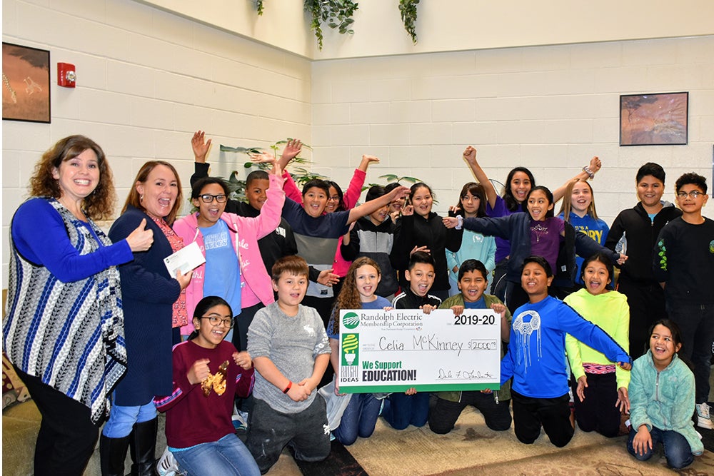 class celebrates winning a grant by holding a large check