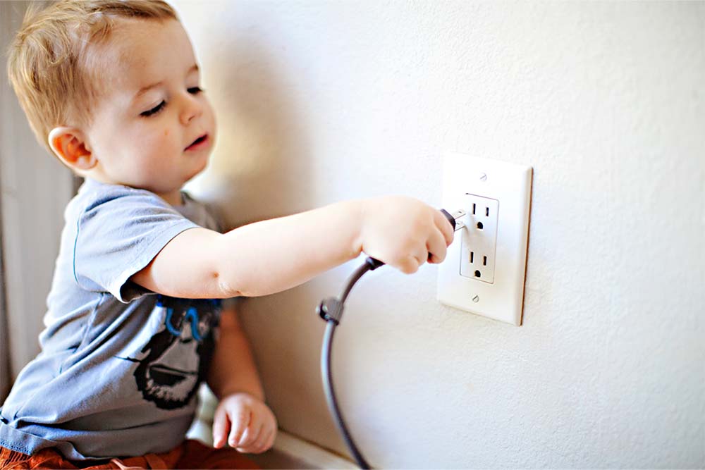 child inserting plug into outlet