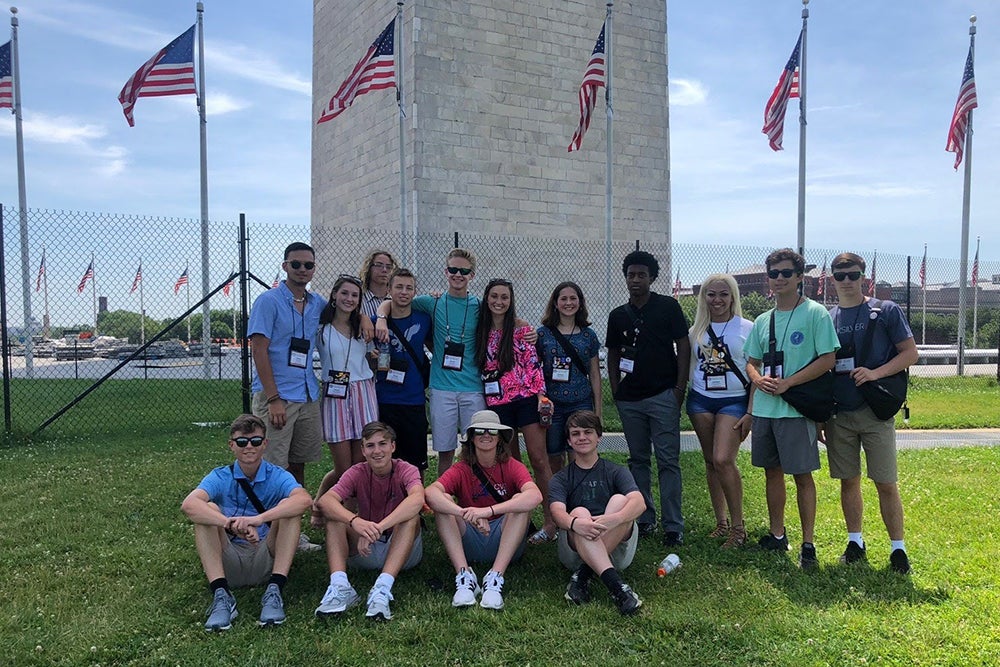 youth tourists take photo in front of Washington Monument in Washington DC